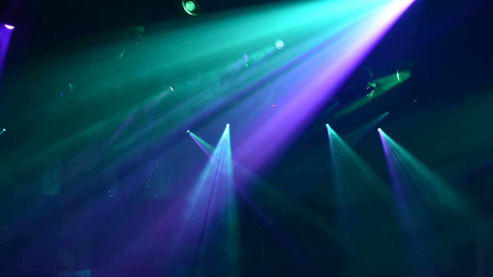Faisceaux de projecteurs colorés dans une salle de discothèque : les discothèques et la convention collective HCR