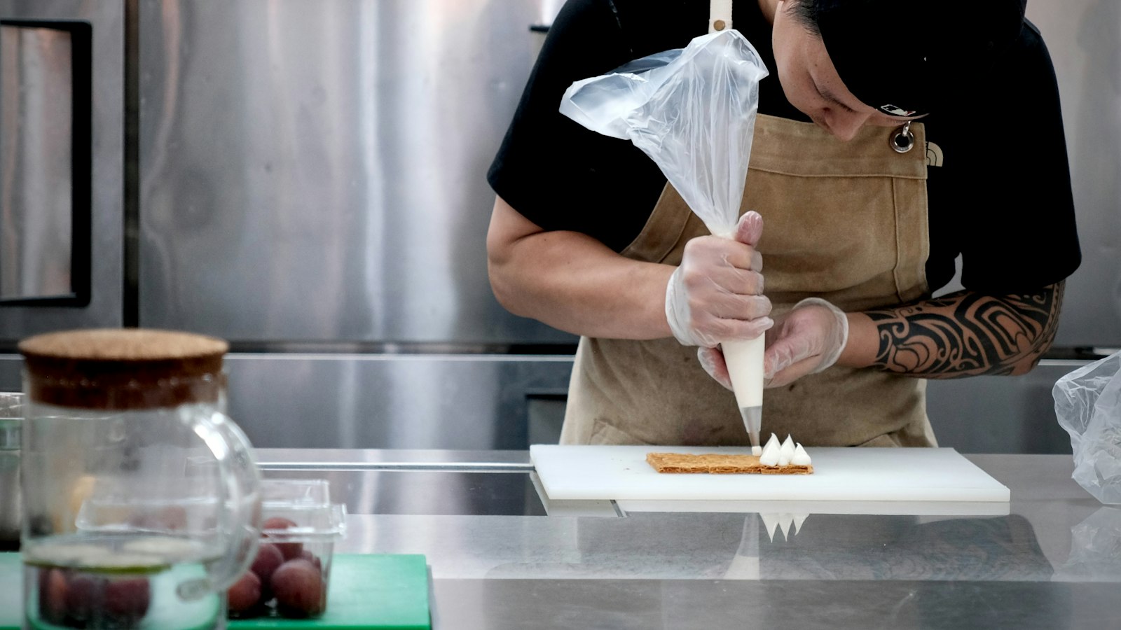 Pâtissier garnissant une pâtisserie à la poche en cuisine : l'apprentissage et l'alternance en HCR