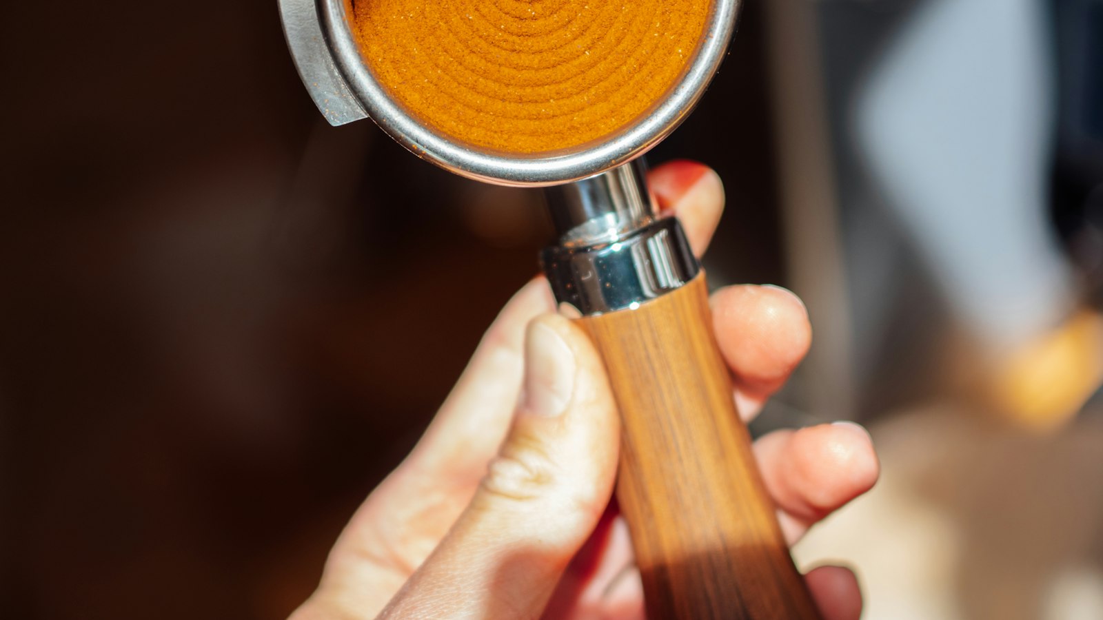 Main tenant le porte-filtre d'une machine à expresso : le travail à temps partiel en HCR