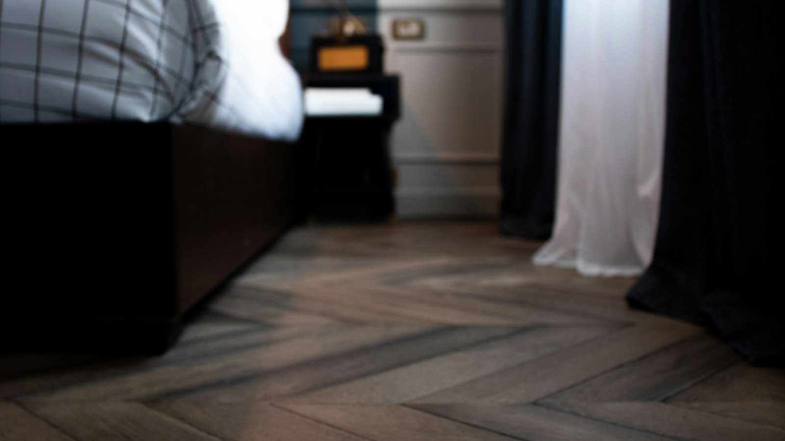 Chambre sobre au parquet en point de Hongrie, lampe allumée près du lit : le logement du personnel en hôtellerie