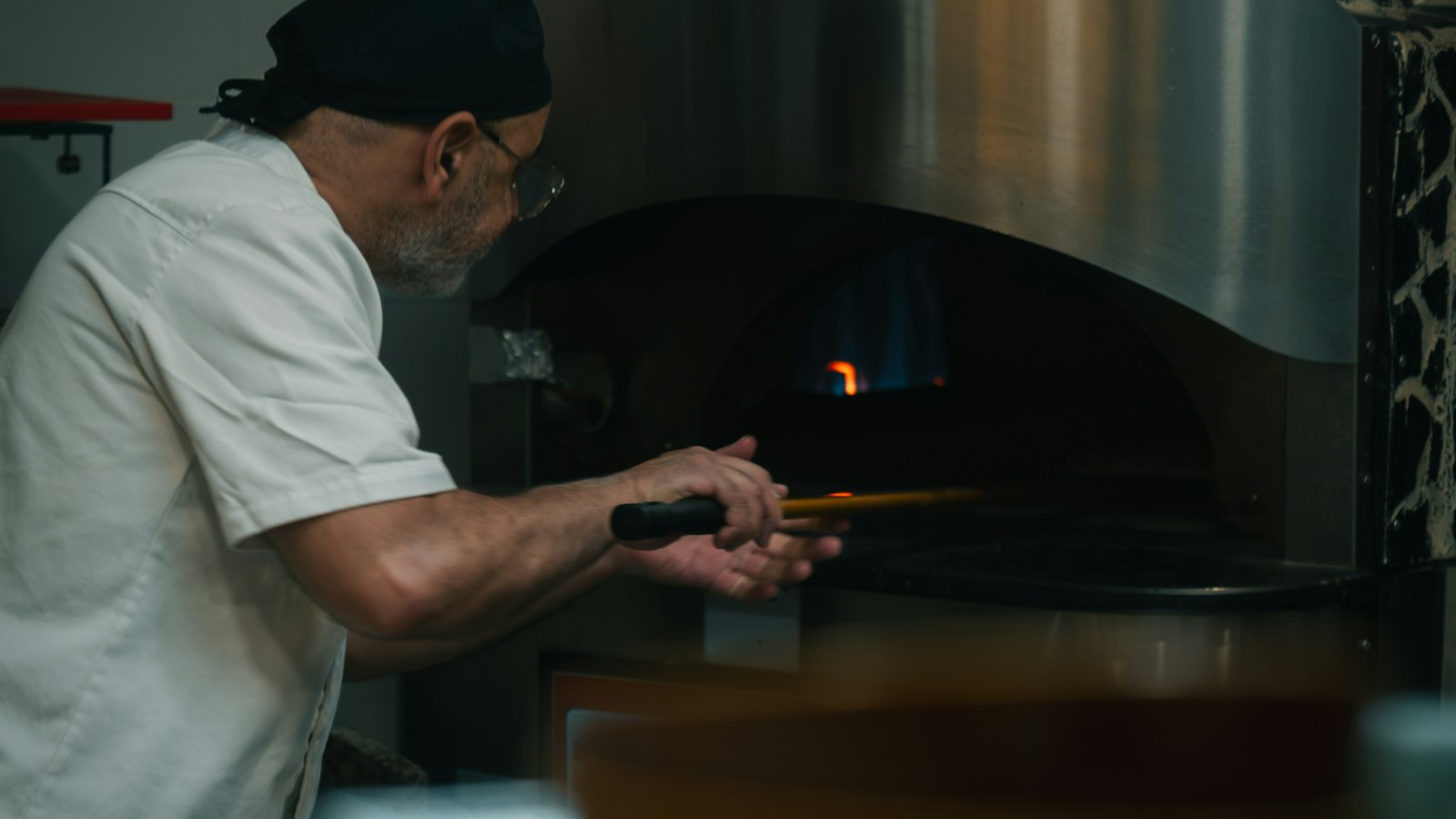 Cuisinier enfournant devant un four à bois dans une cuisine de restaurant : la convention collective des hôtels, cafés, restaurants