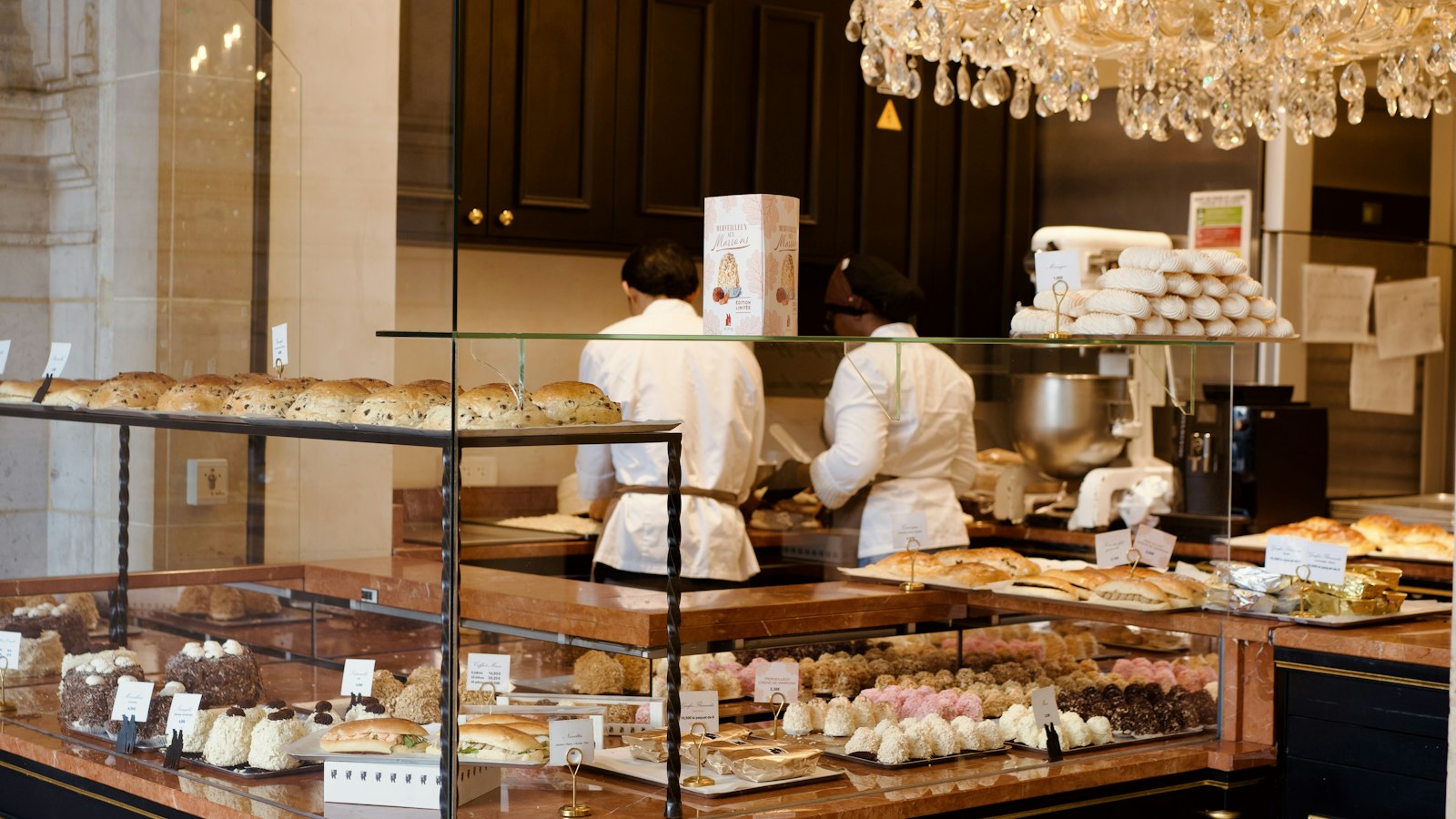 Vitrine de pâtisseries d'une boulangerie-café, cuisiniers à l'arrière-plan : la frontière avec la restauration rapide et collective dans les hôtels, cafés, restaurants