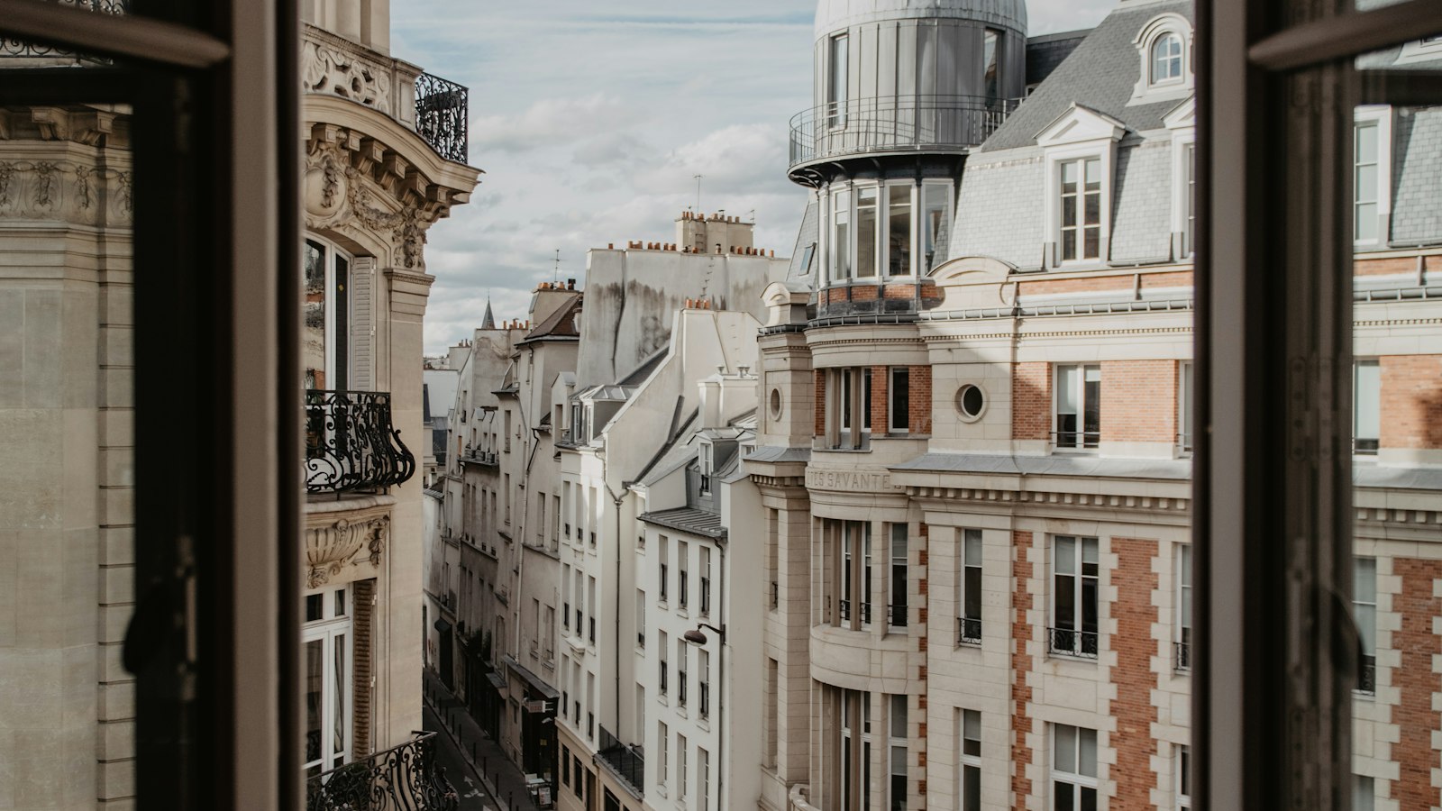 Rue parisienne vue depuis une fenêtre ouverte : l'accompagnement du cabinet dans les hôtels, cafés, restaurants