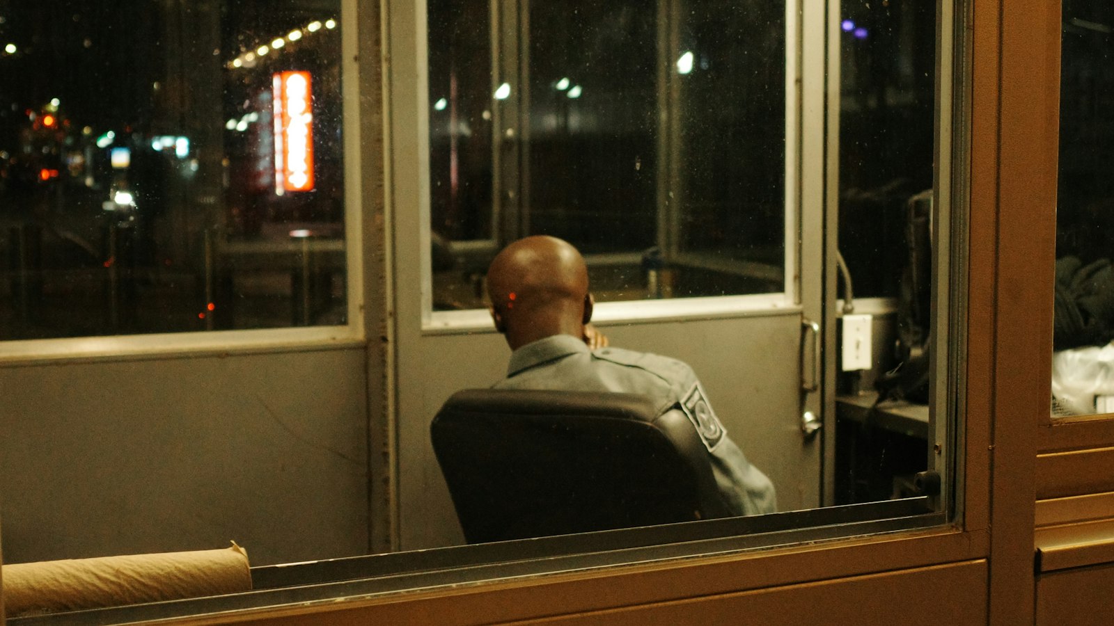 Agent vu de dos dans une guérite vitrée la nuit : le travail de nuit, le dimanche et les jours fériés