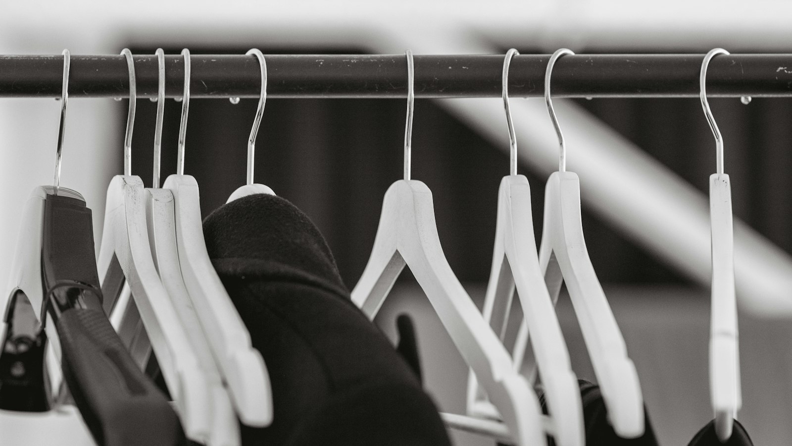 Veste sombre suspendue parmi des cintres : la tenue et les équipements de travail