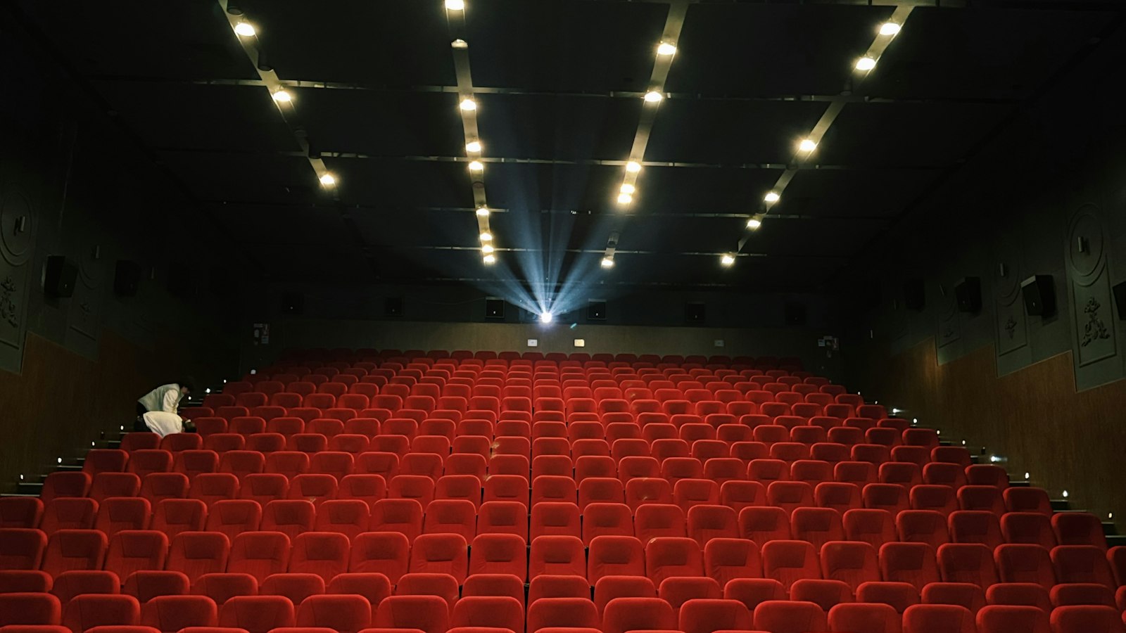 Salle de cinéma vide traversée par le faisceau du projecteur : actualités sociales de l'exploitation cinématographique