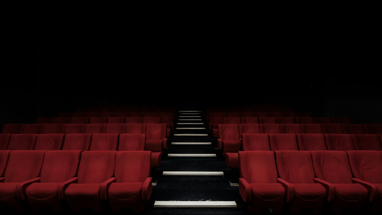 Fauteuil de cinéma rouge isolé dans la pénombre : maladie et maintien de salaire du salarié de cinéma
