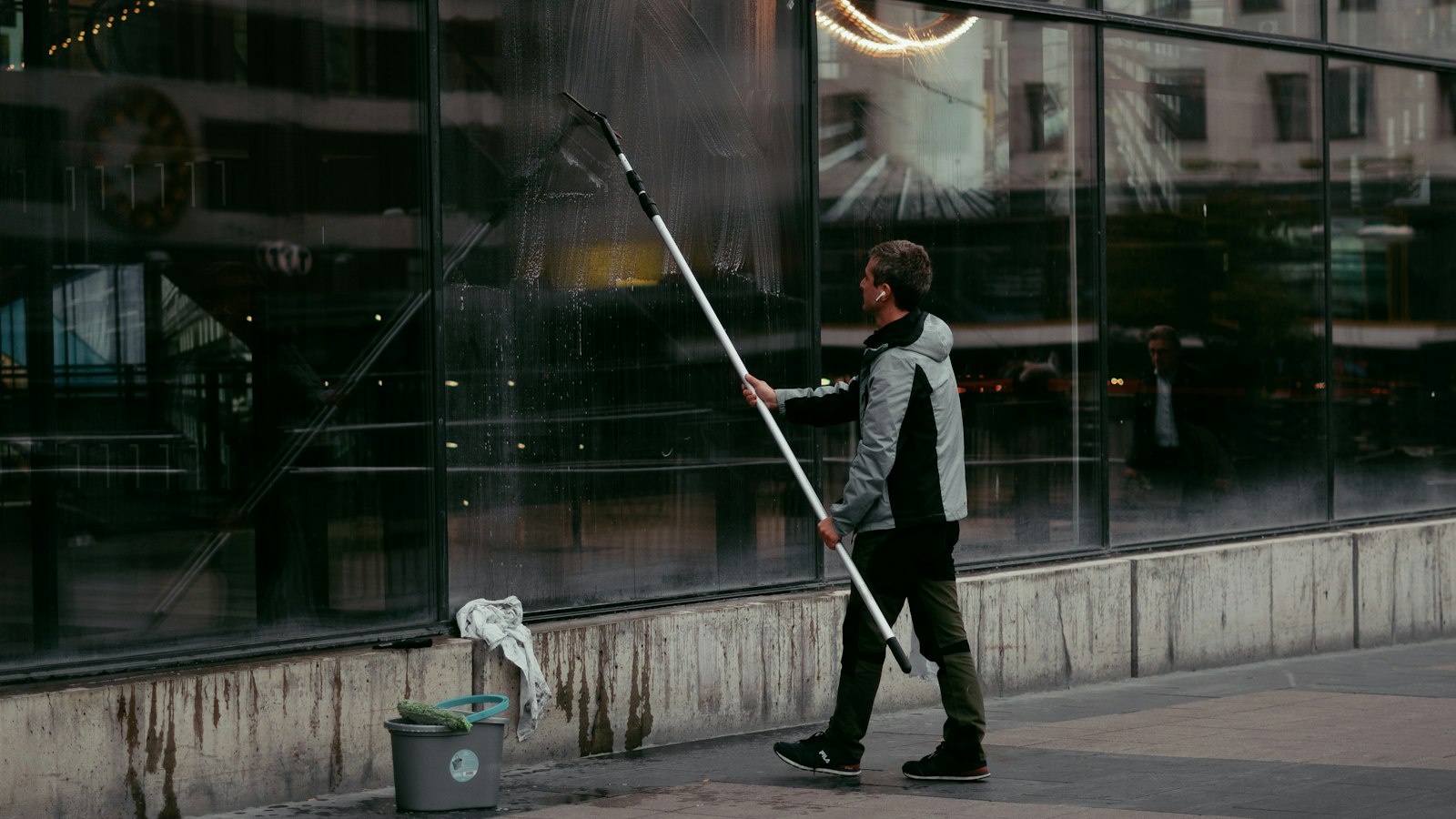 Laveur de vitres nettoyant une façade vitrée à la perche : convention collective des entreprises de propreté
