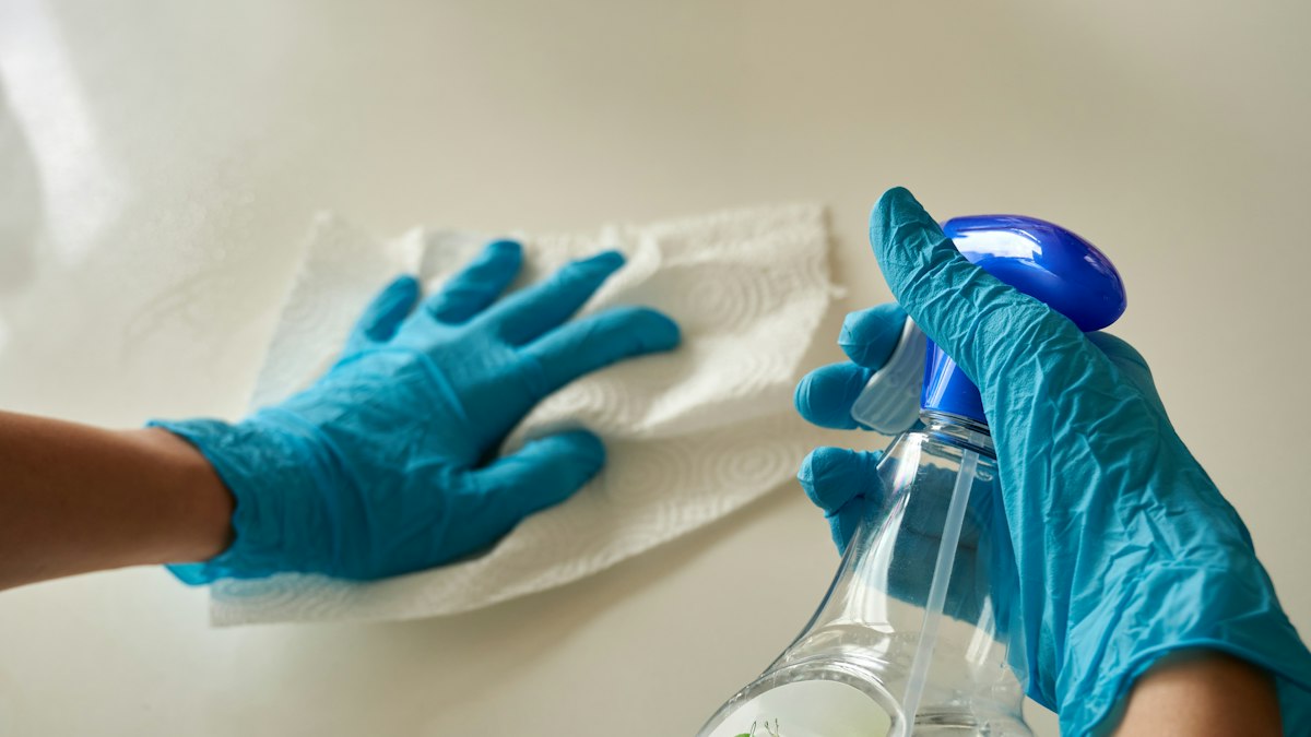 Mains gantées essuyant une surface avec un vaporisateur : le temps partiel dans les entreprises de propreté