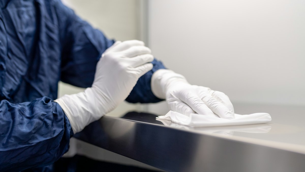 Mains gantées de blanc essuyant une surface en milieu protégé : classification et rémunération des agents de propreté