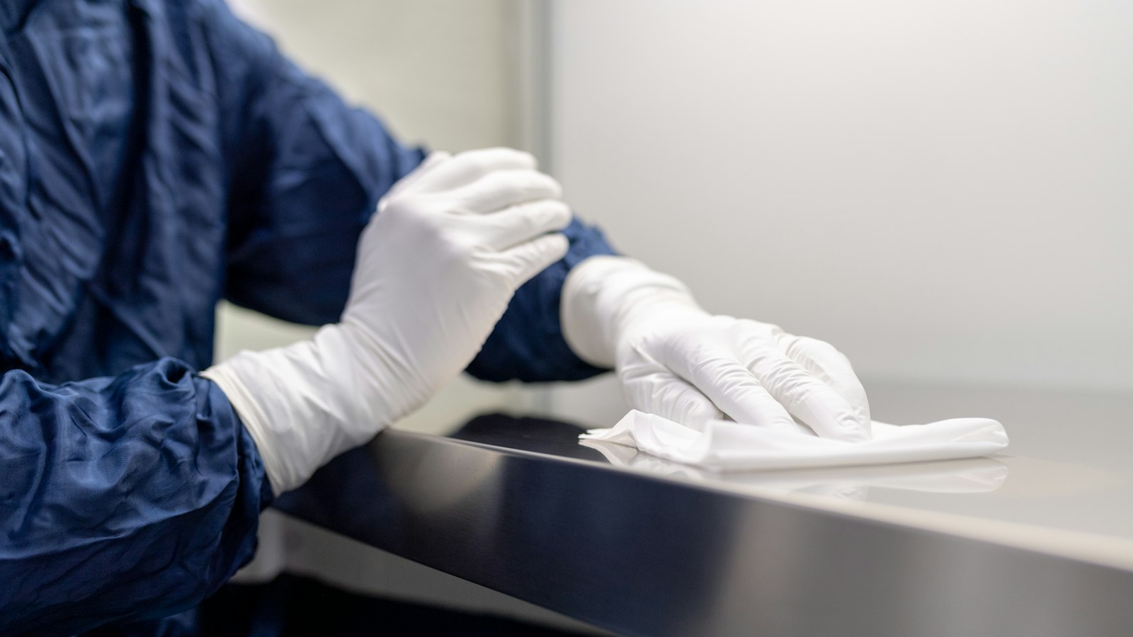 Mains gantées de blanc essuyant une surface en milieu protégé : classification et rémunération des agents de propreté