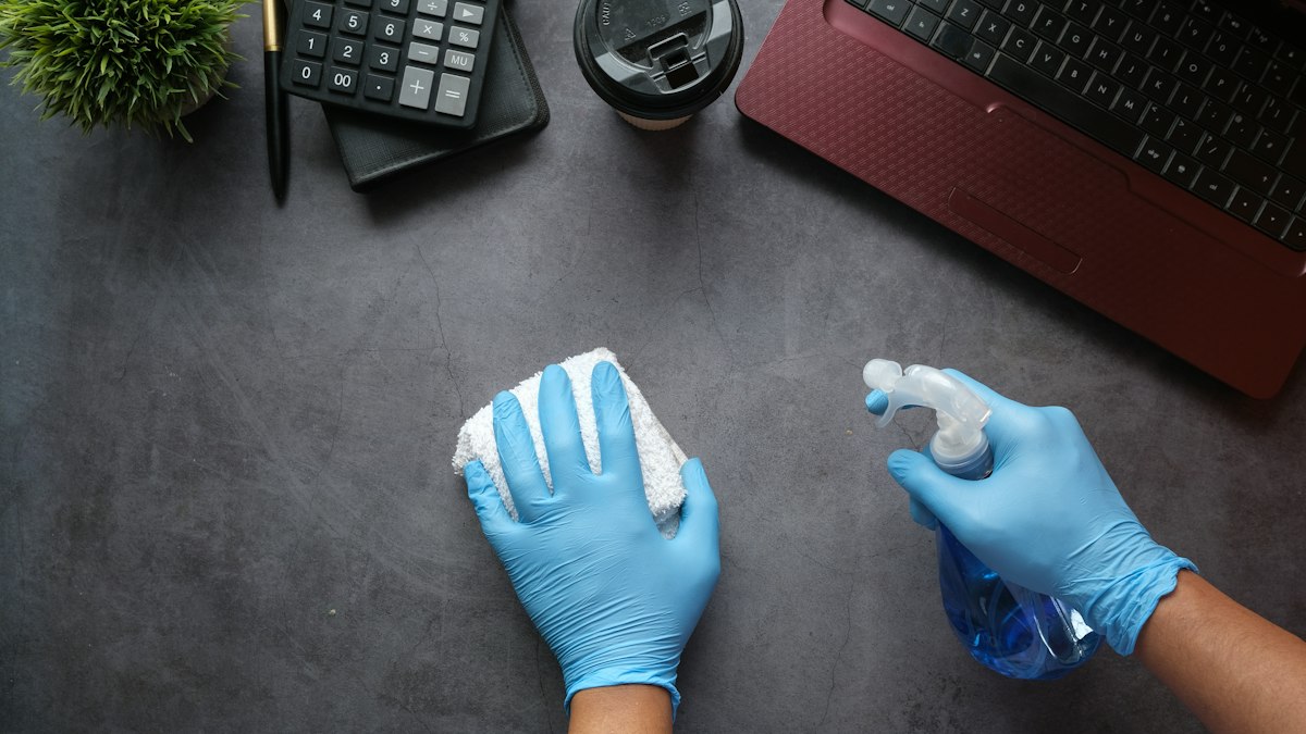 Mains gantées nettoyant un bureau : la santé et la sécurité des agents de propreté