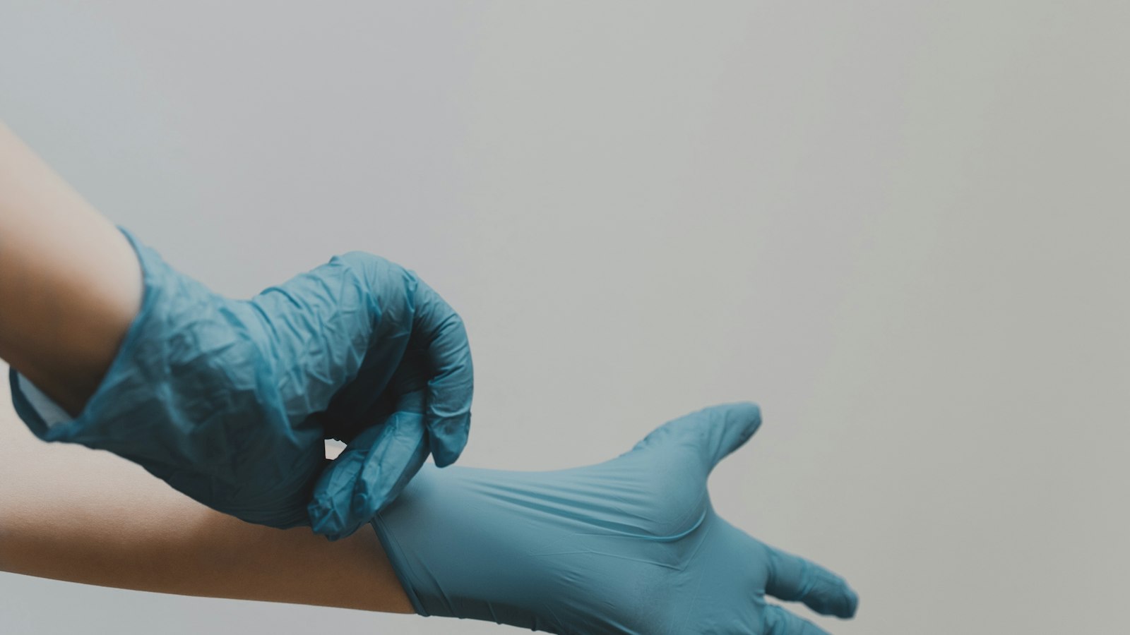 Mains enfilant des gants de protection en nitrile : le document unique et le plan de prévention de l'entreprise de propreté sur les sites clients