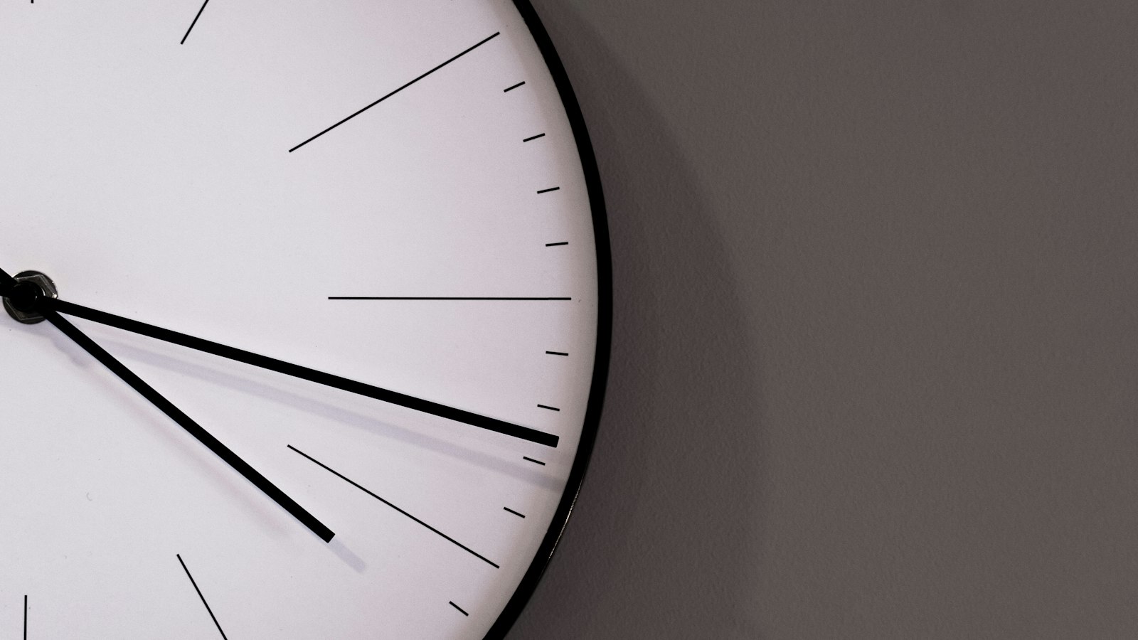 Horloge murale blanche sans chiffres sur un mur gris : horaires, coupures et délai de prévenance dans la propreté