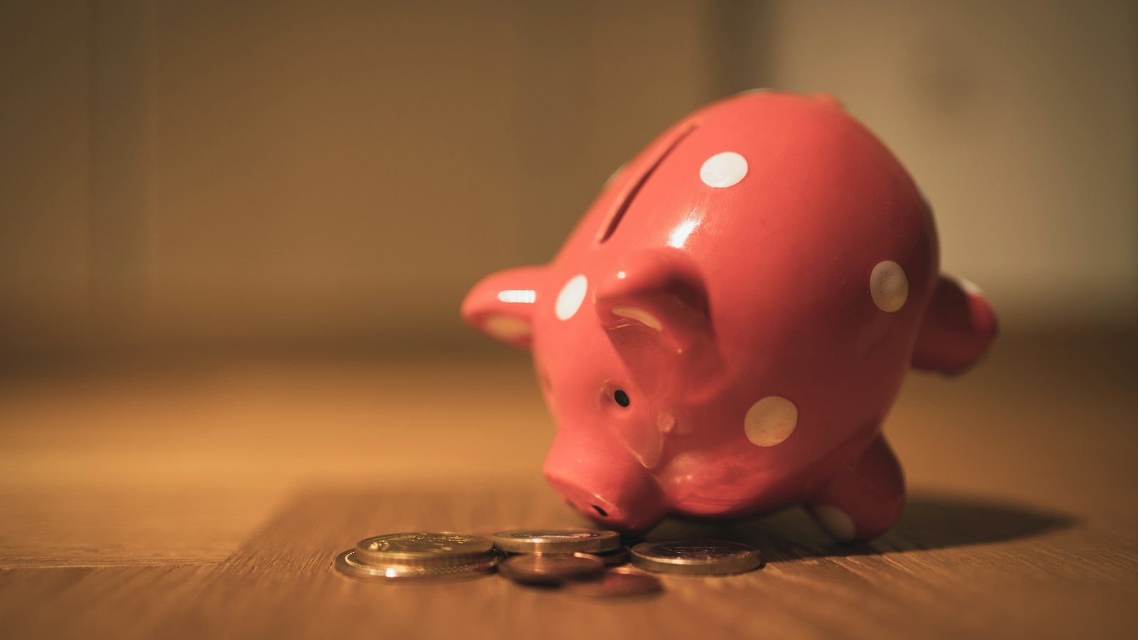 Tirelire cochon et pièces sur une table en bois : la prime annuelle des agents de propreté
