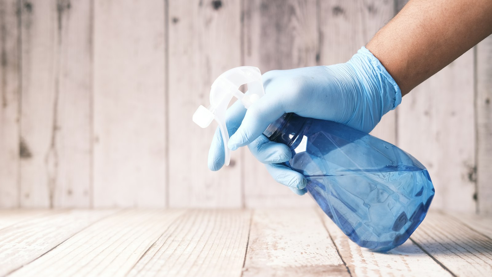 Main gantée tenant un pulvérisateur : produits chimiques et risque chimique dans la propreté