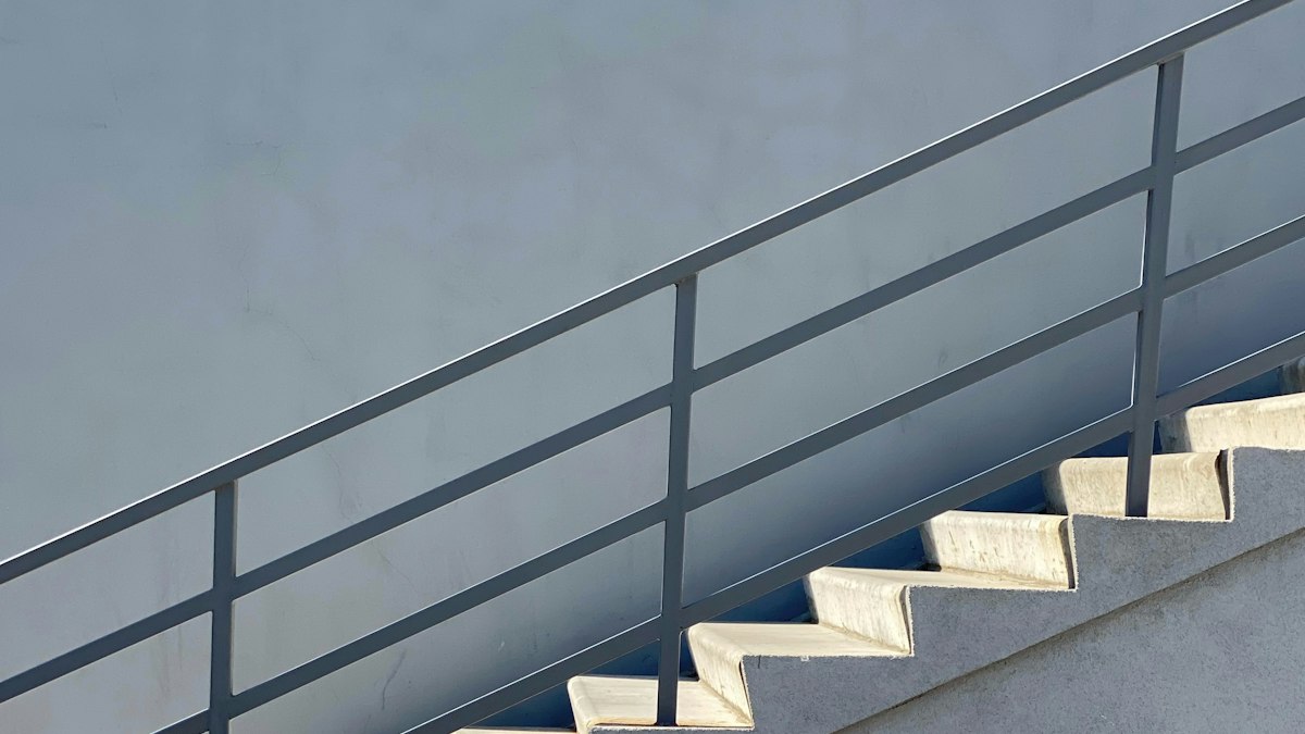 Escalier de béton blanc à rampe noire : les voies du départ négocié