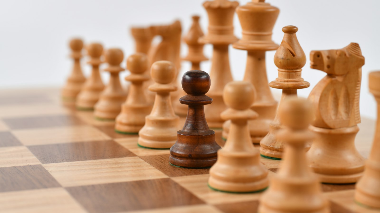 Pièces d’échecs en bois sur un plateau : la stratégie de négociation d’un départ