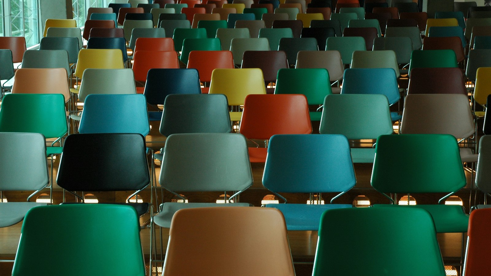 Rangées de chaises de couleurs différentes dans une salle : la composition du CSE et la durée des mandats