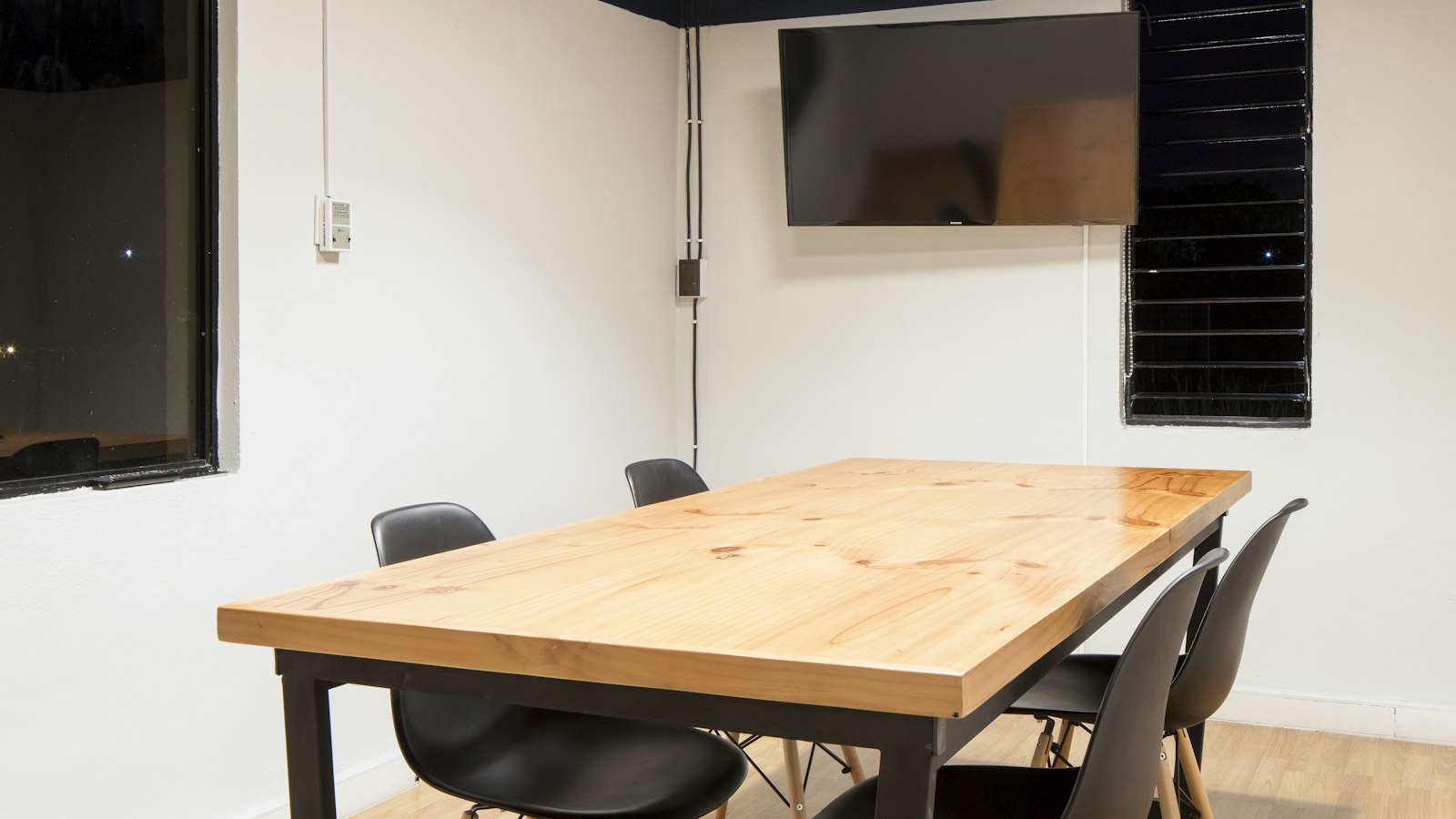 Petite salle de réunion avec table en bois et chaises noires : les commissions du CSE