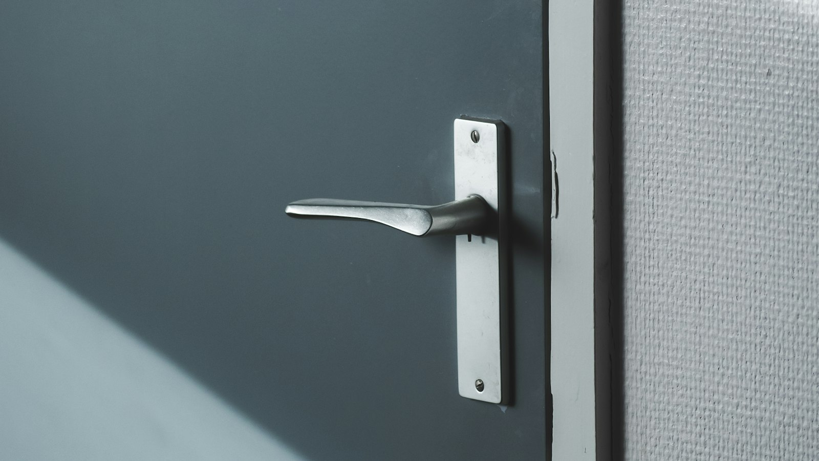 Poignée d’une porte grise baignée de lumière : le local, l’affichage et la communication du CSE