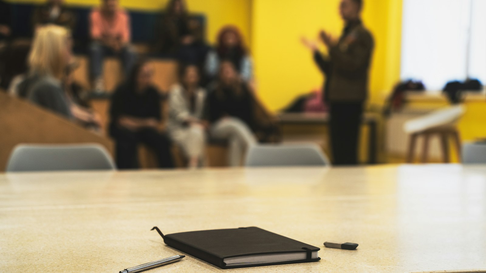 Carnet et stylos sur une table, salle de formation floue à l’arrière-plan : le statut protecteur et la formation des élus du CSE