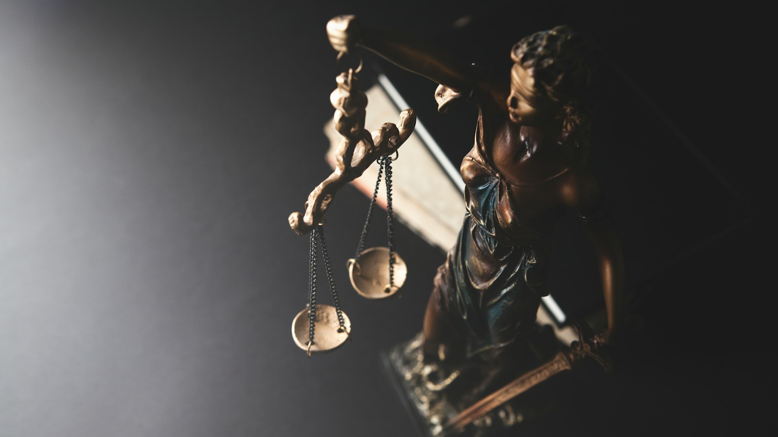 Statuette de la Justice et sa balance dans la pénombre : le recours devant le pôle social du tribunal judiciaire