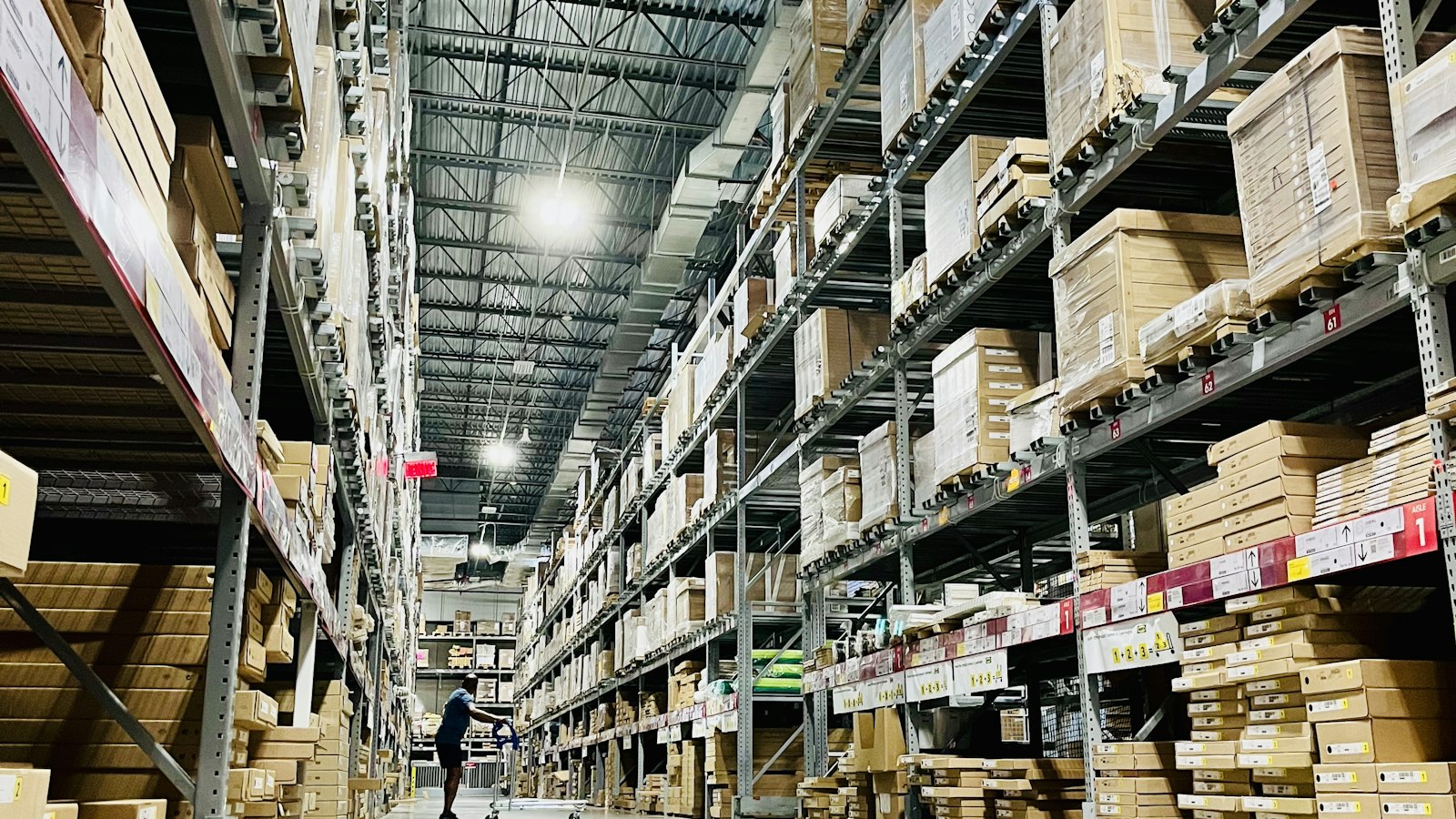 Allée d’entrepôt bordée de rayonnages chargés de cartons : la fourniture exclusive des marchandises