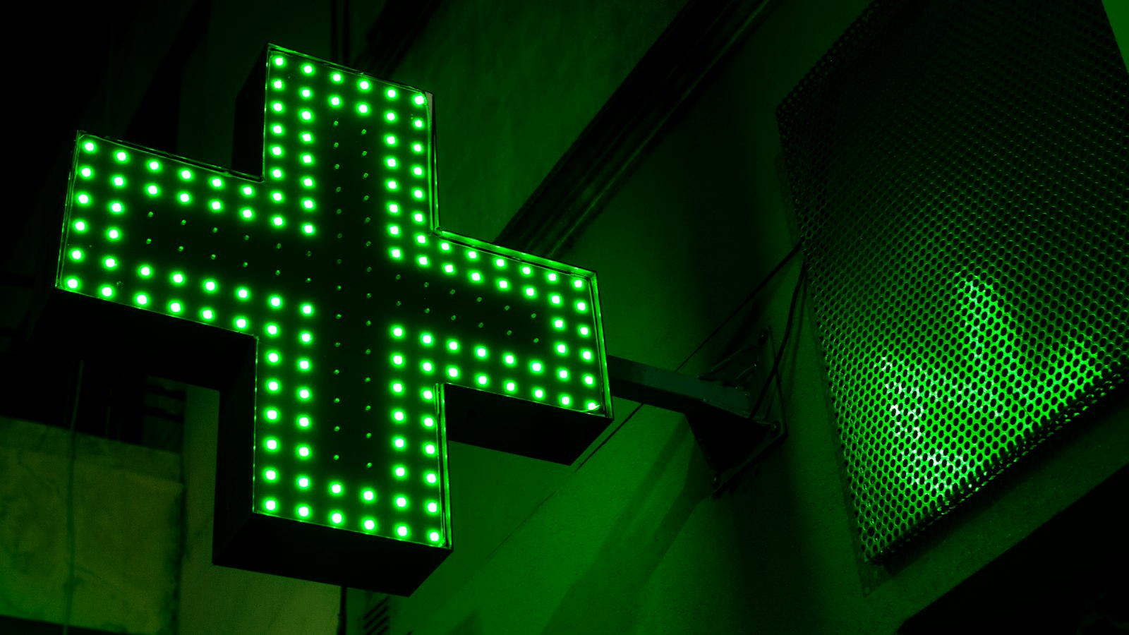 Croix verte de pharmacie allumée dans la pénombre : les gardes, le dimanche et les jours fériés dans l'officine