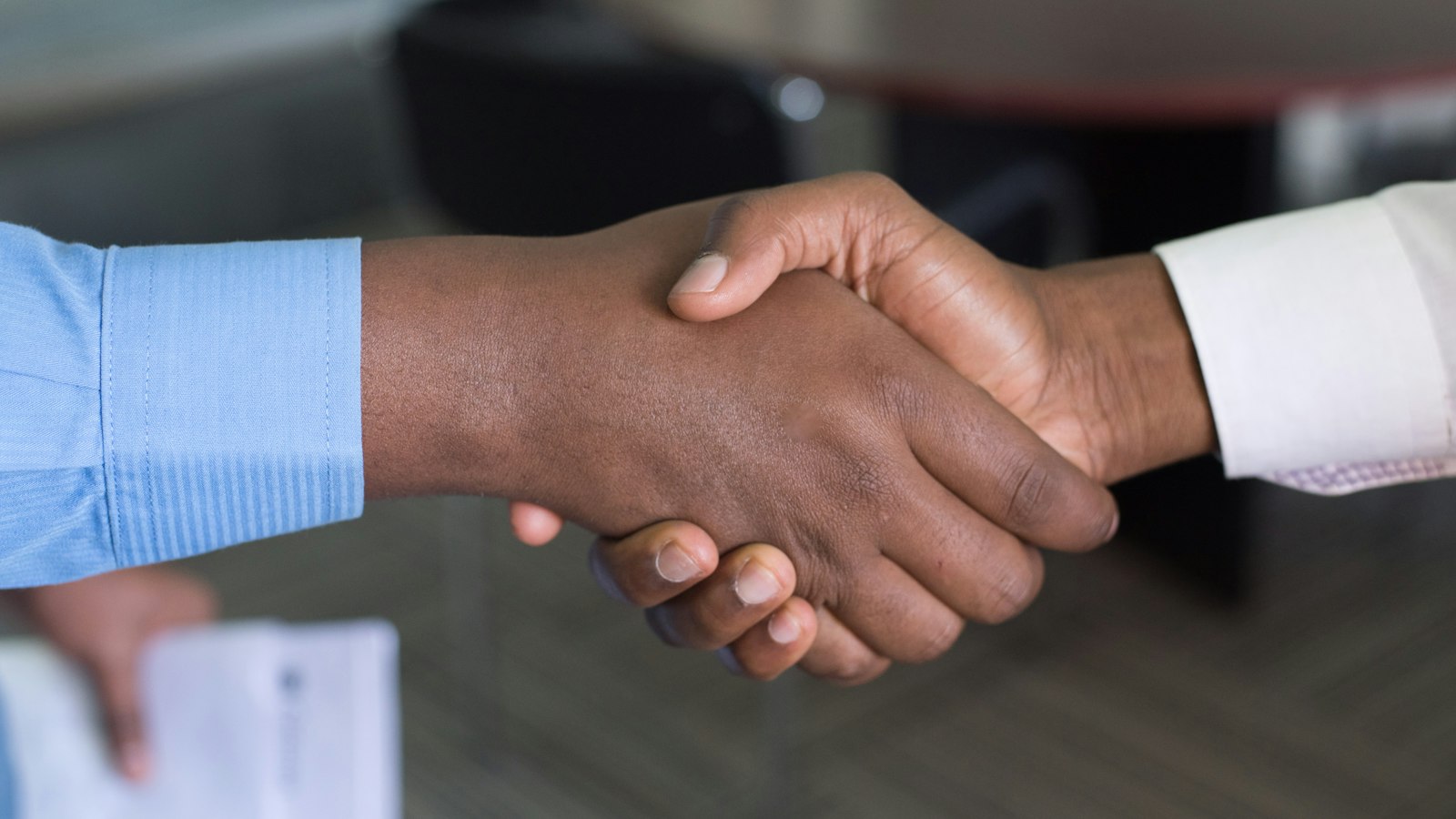 Poignée de main au-dessus d'une table de bureau : le contrat de travail du salarié de l'officine