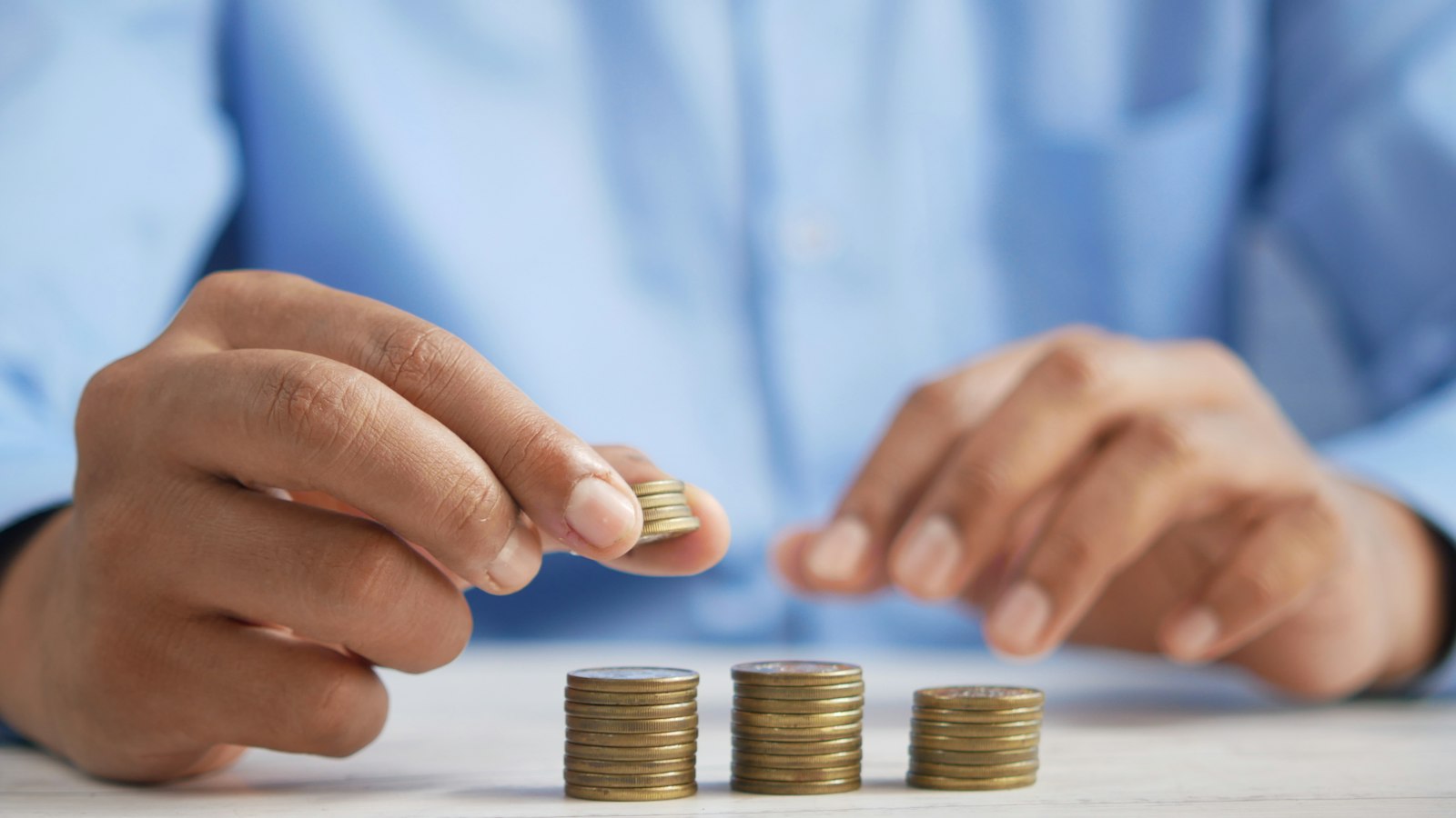 Mains empilant des pièces de monnaie : les salaires minima et la valeur du point de la pharmacie d'officine