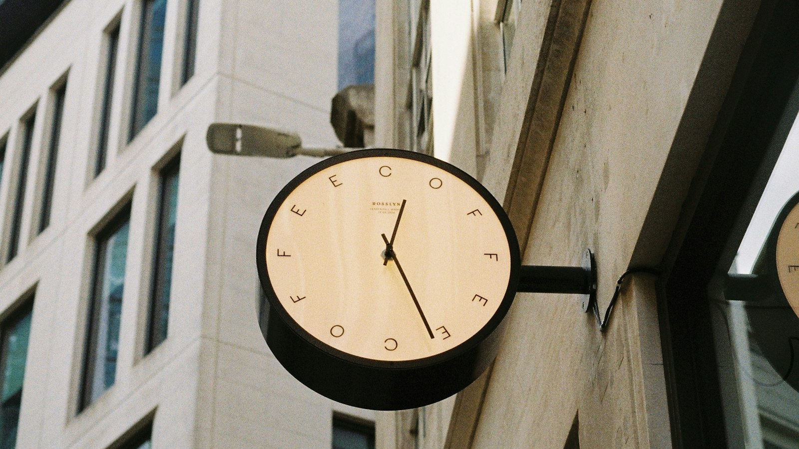 Horloge en drapeau sur une façade de centre-ville : le temps partiel dans l'officine