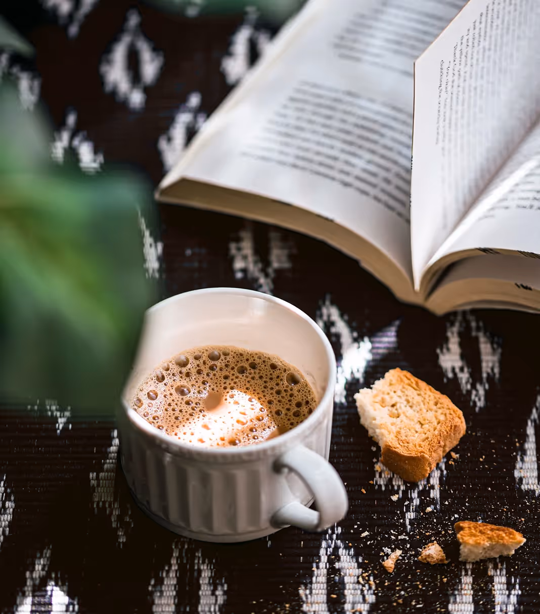 An image of espresso-filled cup in a cozy setting with books and plants, from Stills by Preethi Venkatram