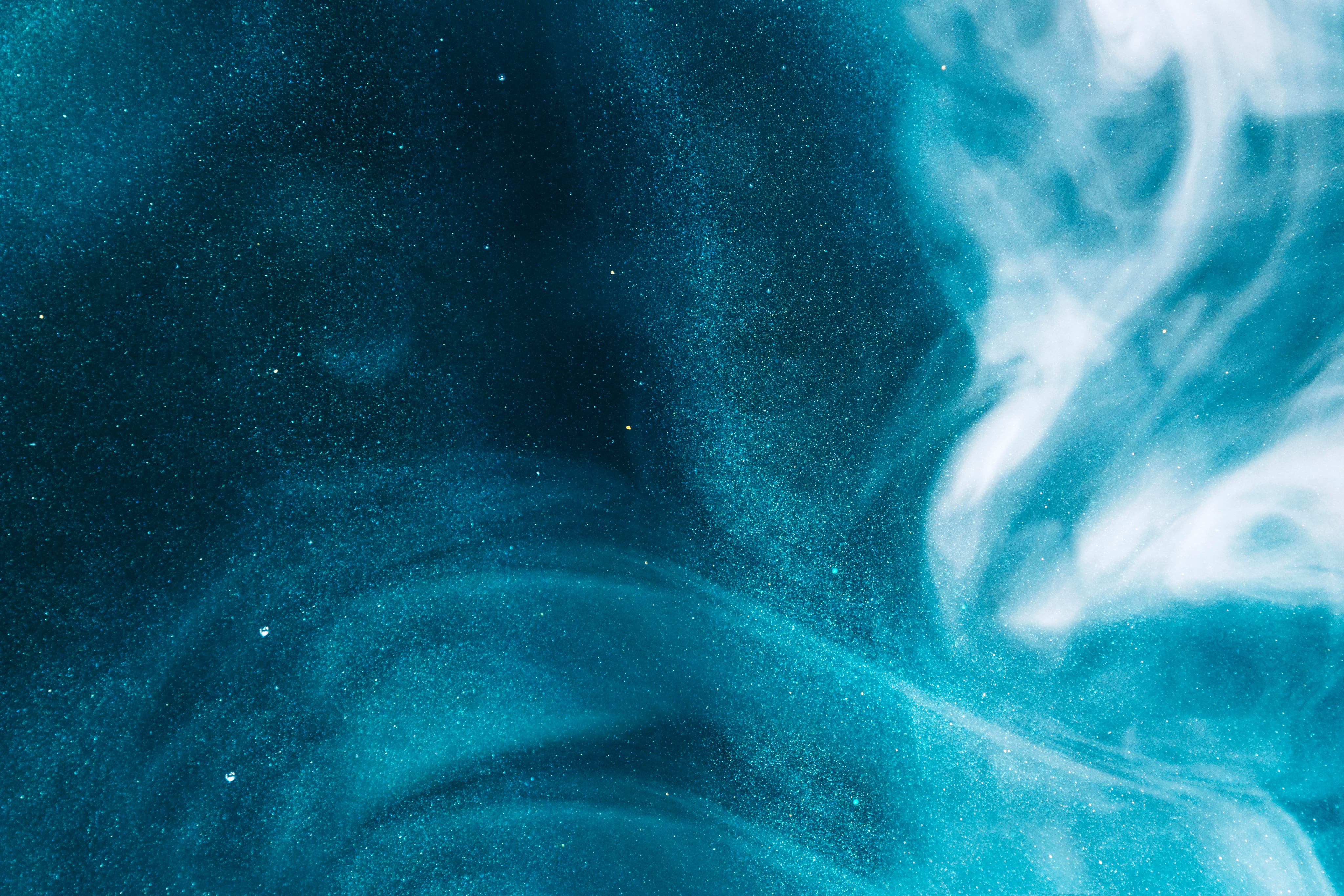 Abstract blue and white swirling patterns resembling smoke or liquid flow with speckled texture.
