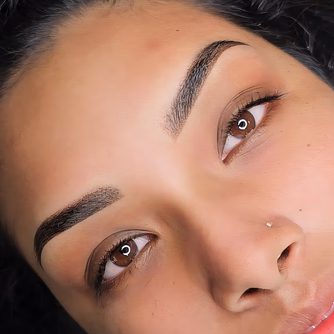 Close-up of a woman's face showing well-defined ombre eyebrows and brown eyes looking upward.