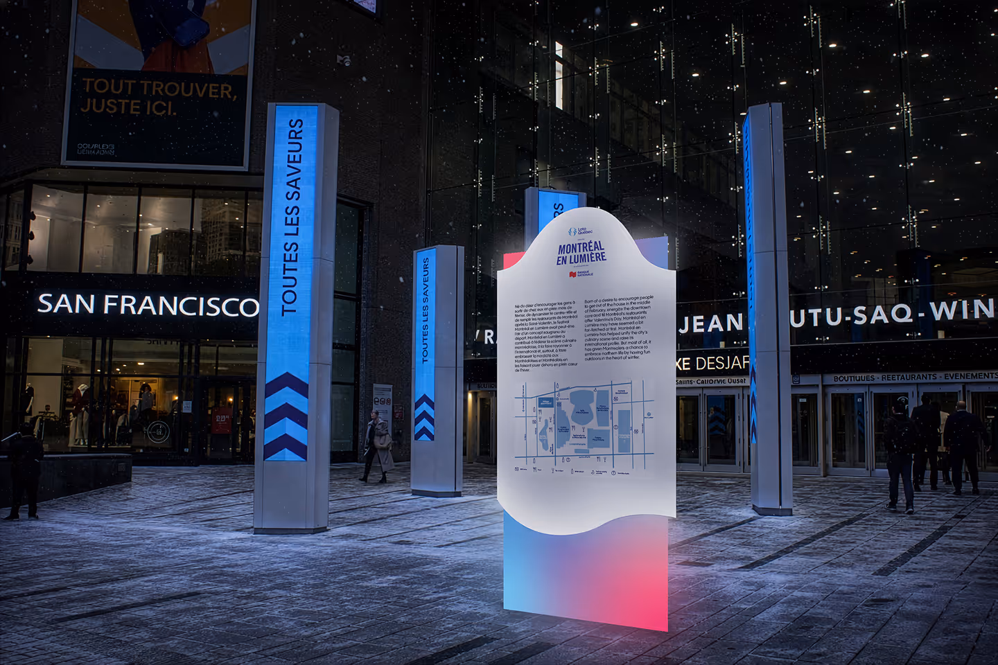 Illuminated Montreal en Lumière event sign and pillars with French and English texts on snowy city street.