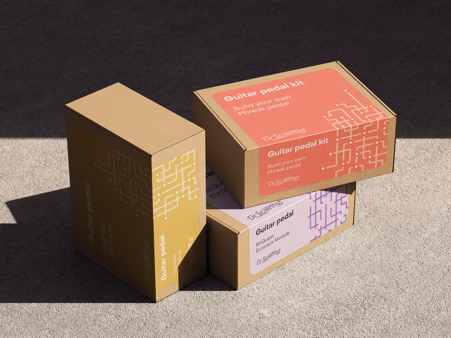 Three Dr.Scientist guitar pedal kit boxes with different colored labels on a textured surface.