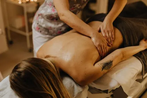 Therapist massaging client’s back with oil