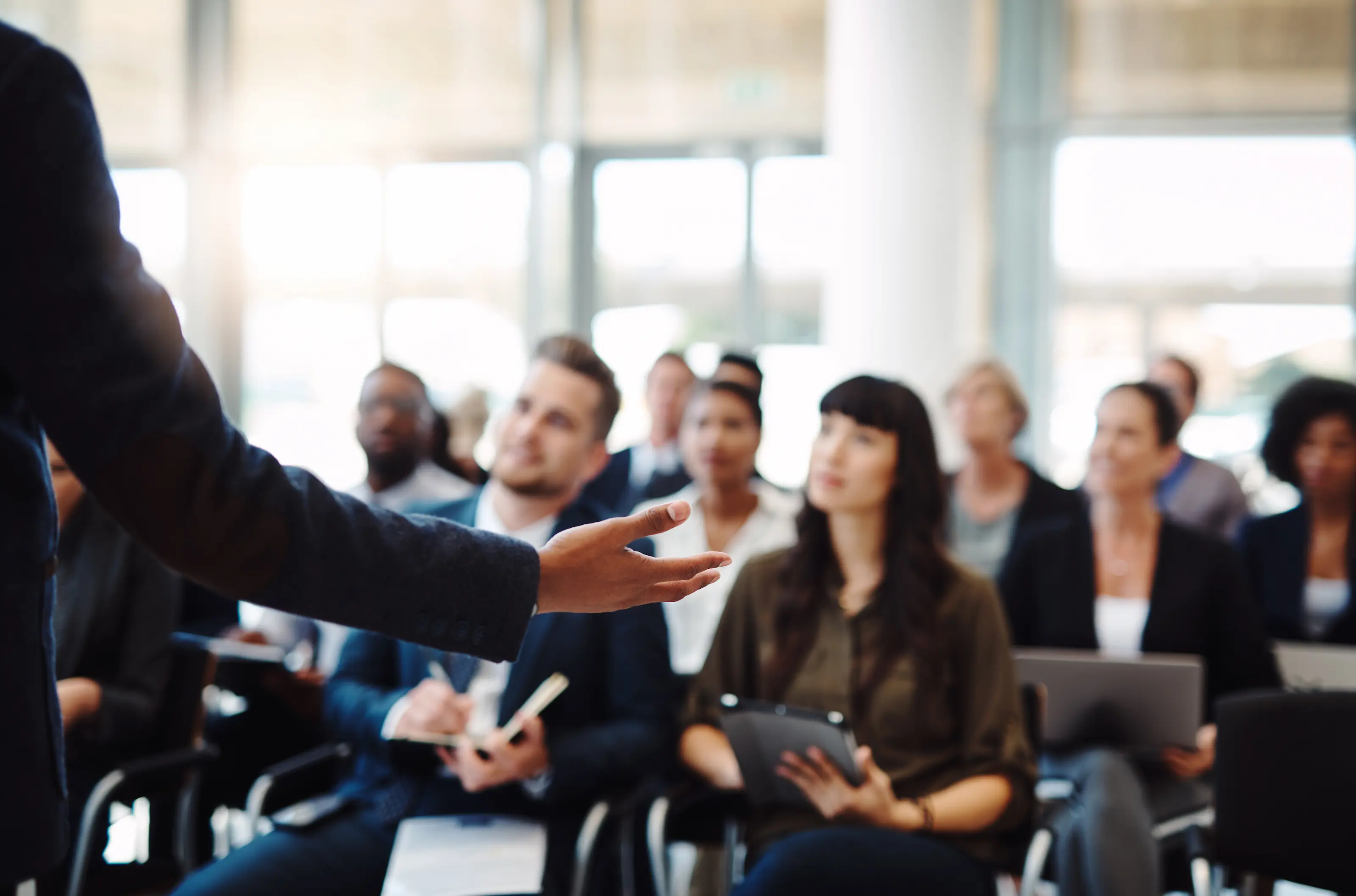 Person erklärt einer Gruppe von Kundinnen und Kunden Inhalte in einer Präsentation, passend zur Kundenakademie.