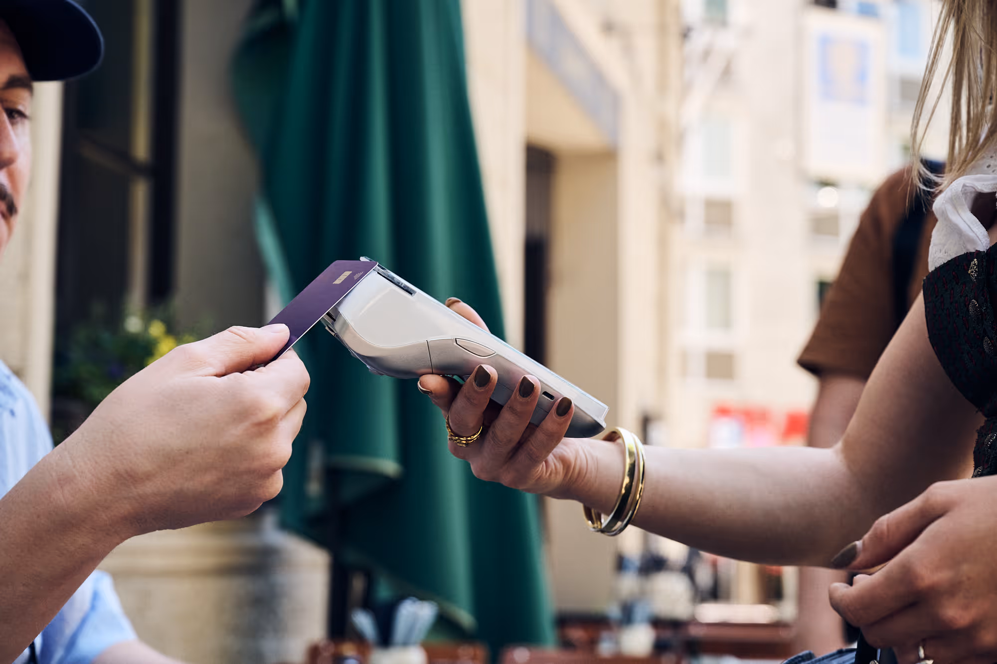 Gast bezahlt kontaktlos mit Karte am mobilen Kartenterminal auf der Außenterrasse