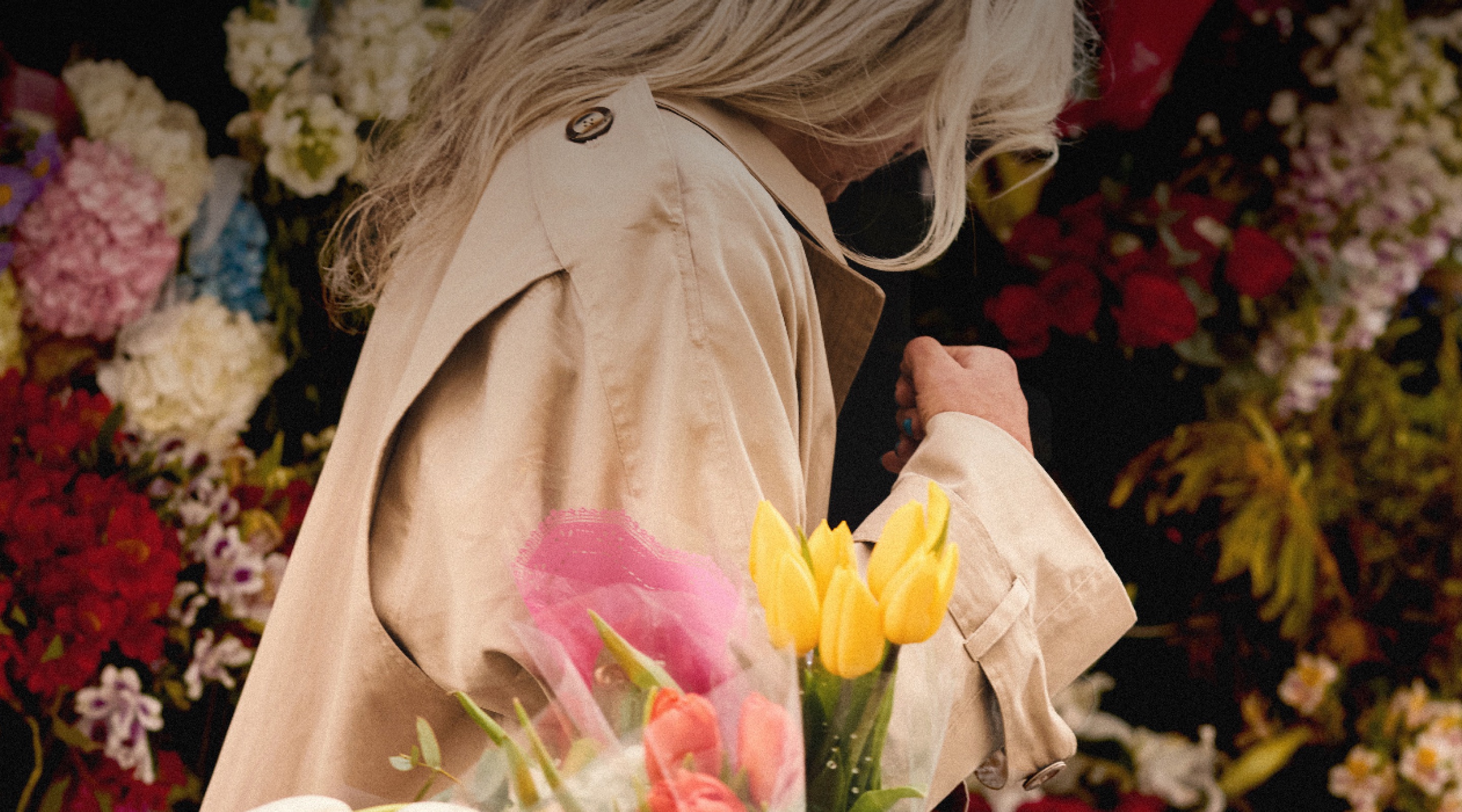 A shopper carrying tulips past a florist's flower display