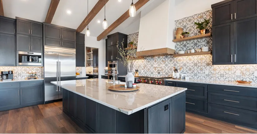 Modern kitchen with dark cabinets, patterned tile backsplash, large marble island, and wooden ceiling beams.