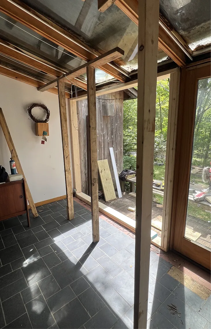 Interior view of a room under construction with wooden beams and glass ceiling panels.