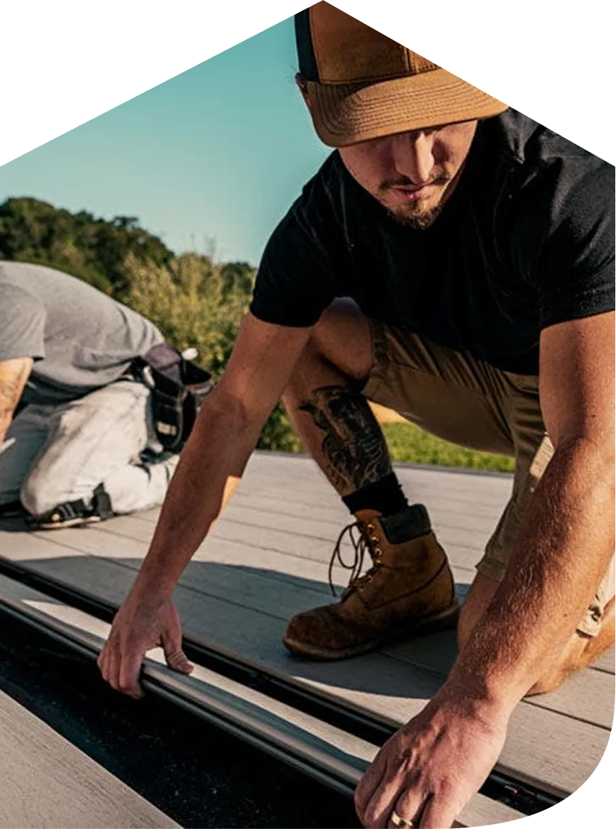 Man wearing a brown cap and boots installing or adjusting a metal pipe on a rooftop.