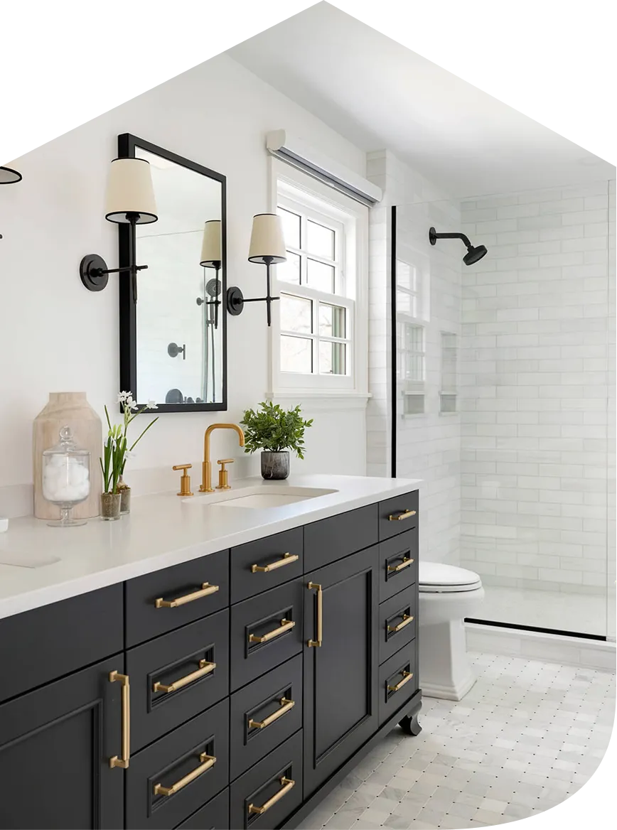 Modern bathroom with black vanity, gold fixtures, white countertop, mirror, and glass shower with white tiles.