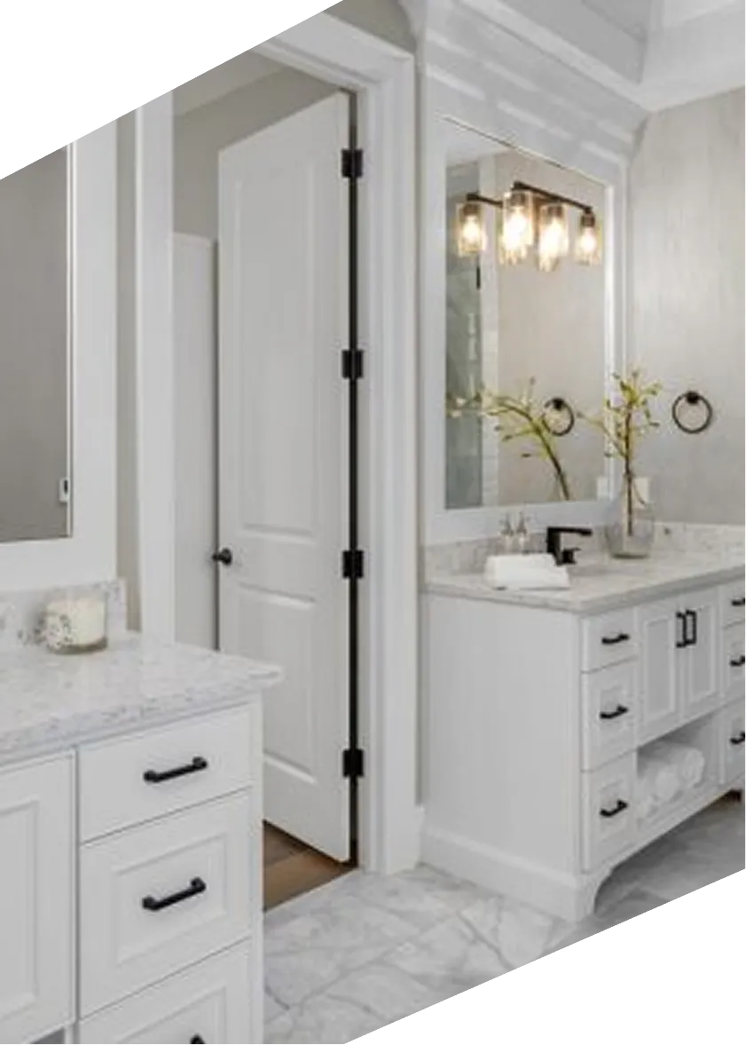 Bright bathroom with white cabinetry, marble countertops, large mirror, and black hardware fixtures.