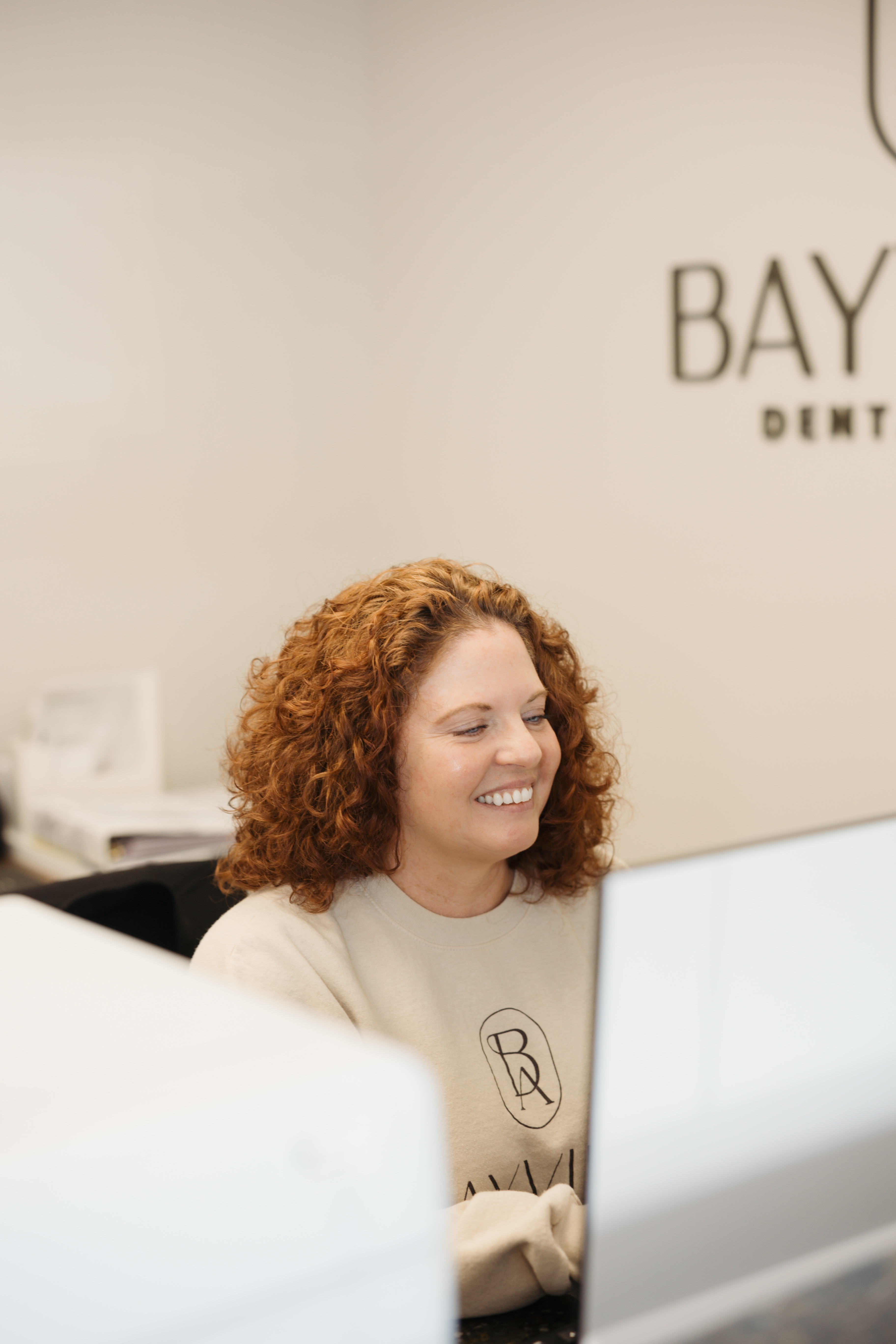 Beige dental chair in a bright, clean dental exam room with equipment and white cabinets.