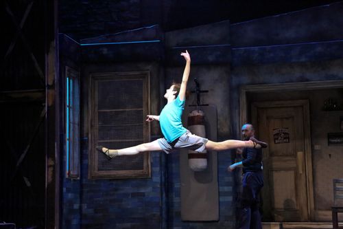 Billy leaps across the stage in a dance sequence from Billy Elliot.