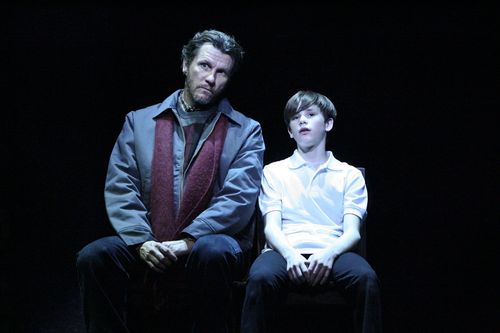Billy and his father sit side by side under a spotlight in Billy Elliot.