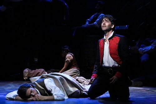 Jean Valjean kneels among fallen bodies at the barricade in Les Misérables.